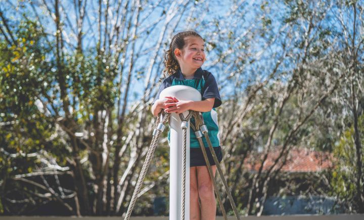 Smiling student plays outdoors on playground equipment